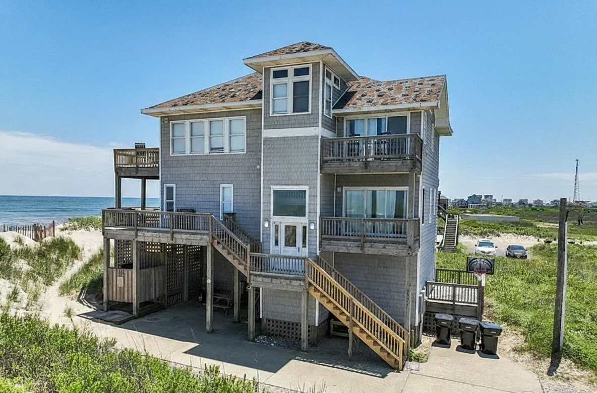 Outer Banks oceanfront home before roof replacement showing worn and weathered shingles with visible discoloration and damage, photographed prior to Curtis Bros. Contracting roofing installation.