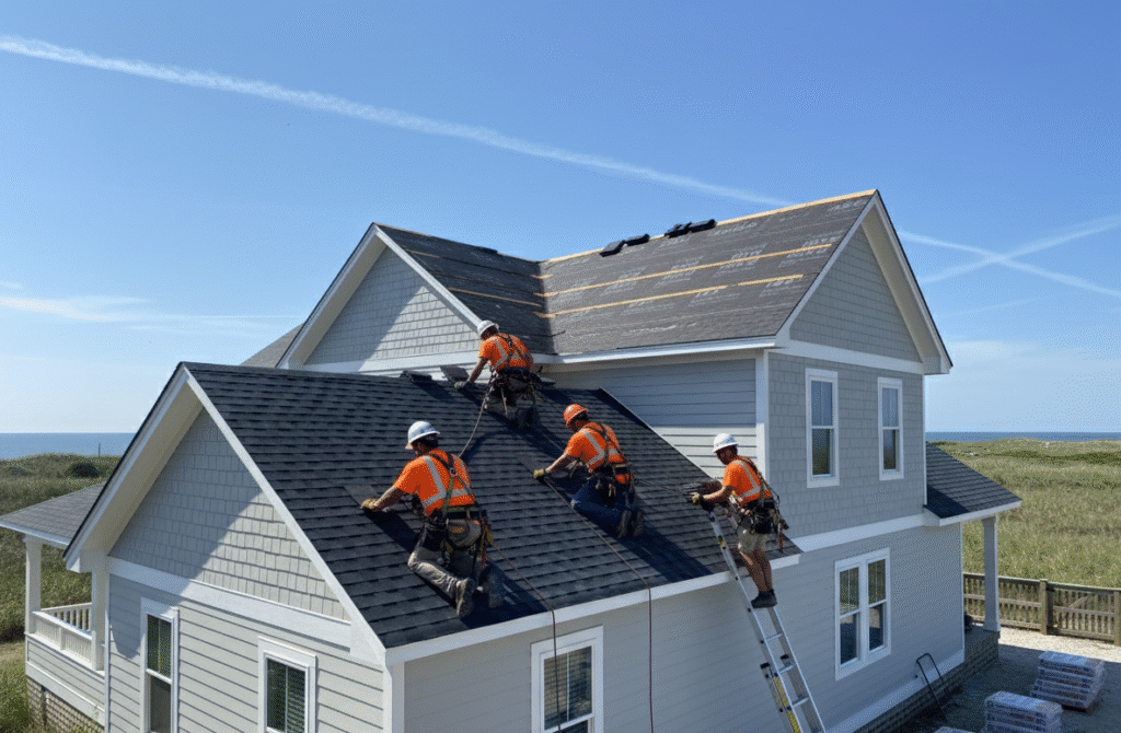 Curtis Bros. Contracting roofing crew installing new asphalt shingles on a coastal Outer Banks home during professional roof replacement.